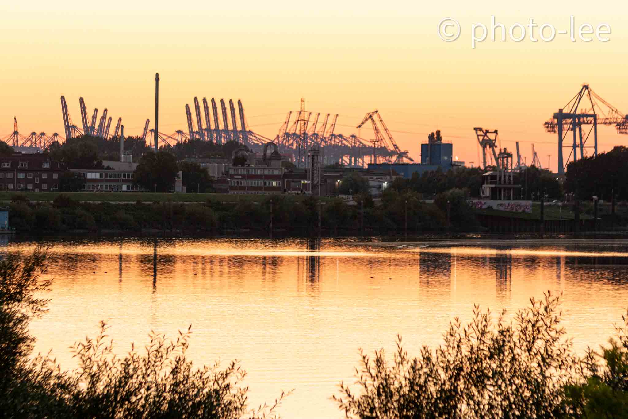 Blick auf den Hamburger Hafen mit Reflexion in der Elbe zur Goldenen Stunde